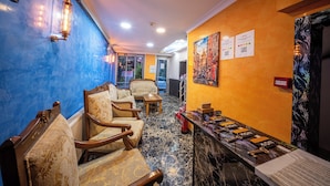 A hotel lobby with a reception desk, seating area, and a blue wall with a textured pattern. - Laos Otel (Istanbul)