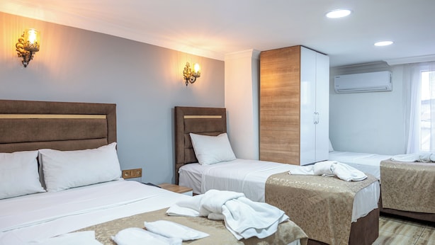 A hotel room with two beds, a wooden headboard, a wardrobe, and a wall-mounted air conditioner. - Laos Otel (Istanbul)