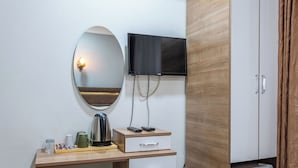 A hotel room with a wooden desk, a flat-screen TV mounted on the wall, a mirror, and a wardrobe. - Laos Otel (Istanbul)