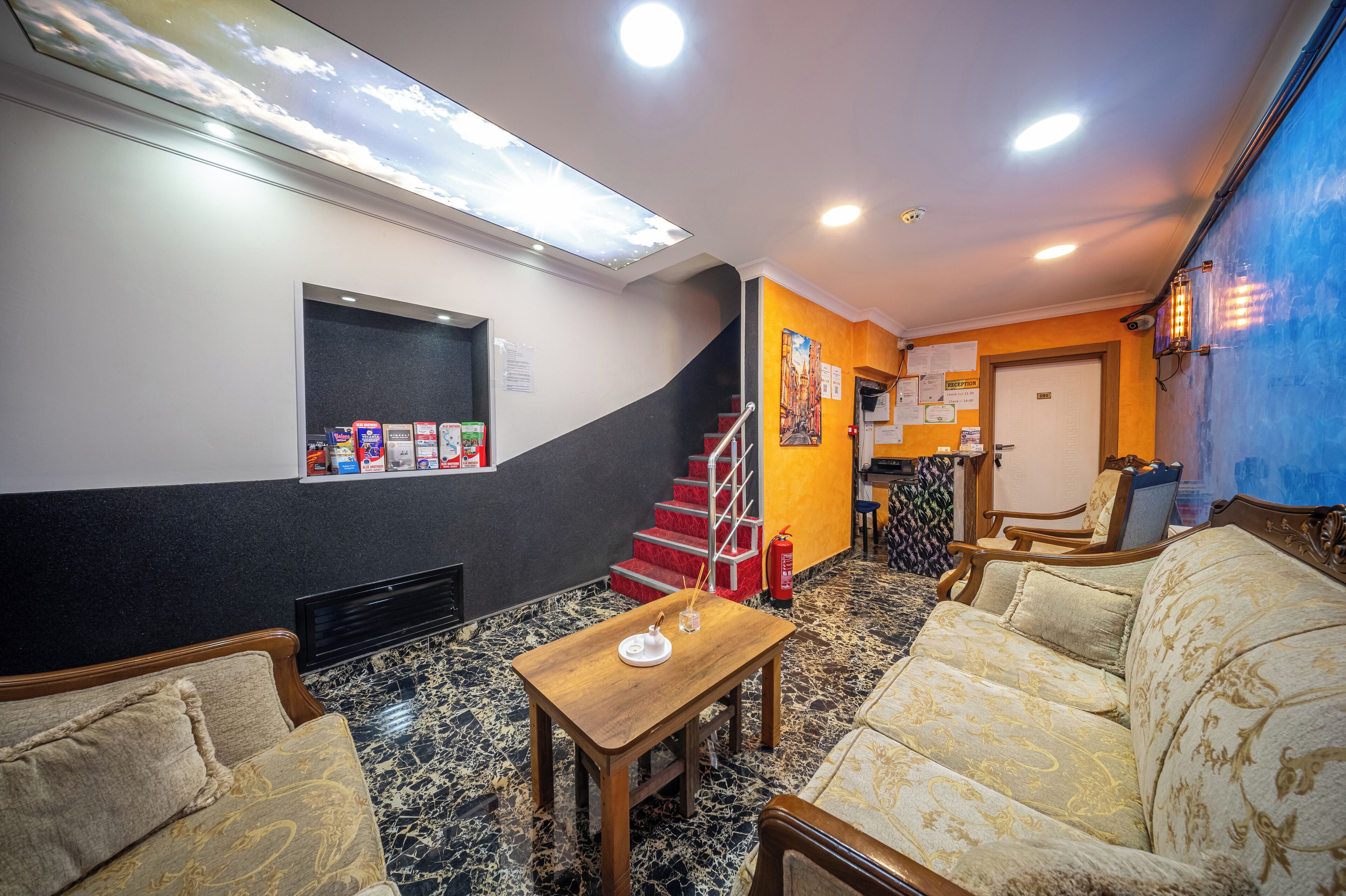 A hotel lobby with a staircase, seating area, and a reception desk.