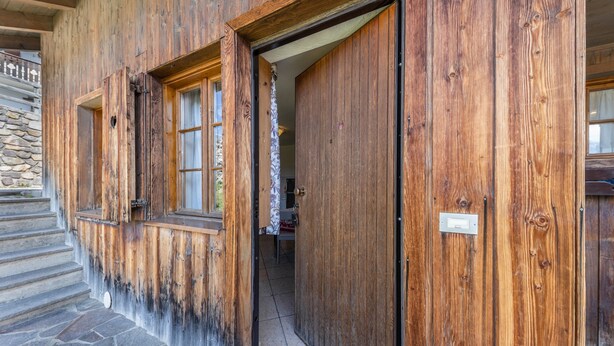 A wooden building with a stone staircase and a door leading to an interior space.