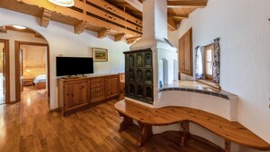 A wooden bench, a television, and a cabinet in a room with wooden floors and a sloped ceiling.