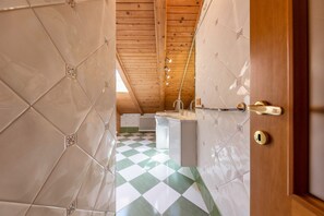Una stanza con pavimento a scacchi, soffitto in legno e una porta con serratura.