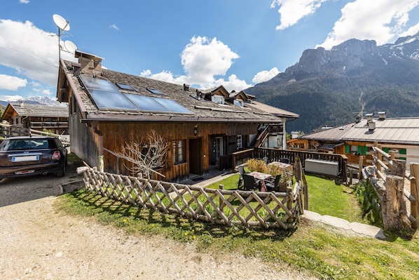 A wooden chalet with a sloped roof, solar panels, and a wooden fence.