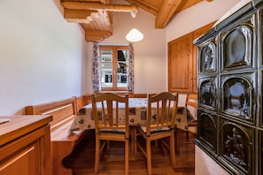 A dining area with wooden furniture, a table with a patterned tablecloth, and a window with curtains.