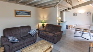 Una sala de estar con dos sofás, una mesa de centro y un comedor con una mesa y sillas.