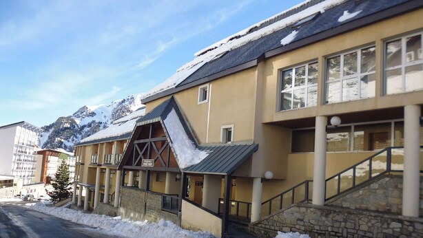 Un hotel con un telesilla, paisajes nevados y montañas al fondo.