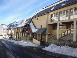 A hotel with a ski lift, snow-covered surroundings, and mountains in the background.