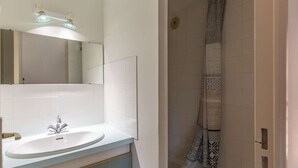 Un baño con lavamanos blanco, un espejo y una ducha con cortinas estampadas.