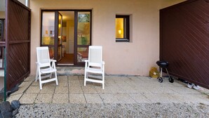 An outdoor seating area with two white chairs, a small window, and a barbecue grill. - Vacation Apartment "Ski-In/Ski-Out" Perfectly Located Year-Round (Valmeinier)