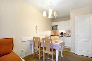 A dining area with a table set for four, a chandelier, and white cabinetry in the background.