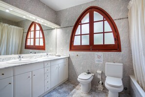 Een badkamer met een grote spiegel, twee wasbakken, een toilet en een douchehoek.