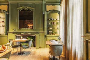 A dining area with a fireplace, wooden furniture, and shelves with decorative items.