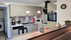 Eine moderne Küche mit weißen Schränken, einer Mikrowelle, einer Kaffeemaschine und einer Uhr an der Wand.