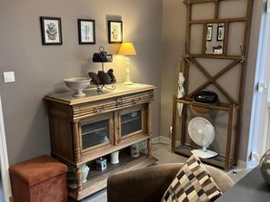 Un salon avec un meuble en bois, une lampe, un ventilateur et un canapé.