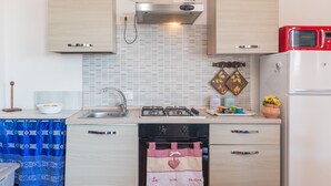 Een kleine keuken met een gasfornuis, oven en een rode magnetron.