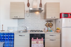 A compact kitchen with a gas stove, oven, and a red microwave.