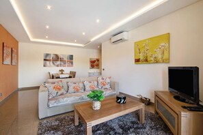 A living room with a sofa, coffee table, TV, and artwork.
