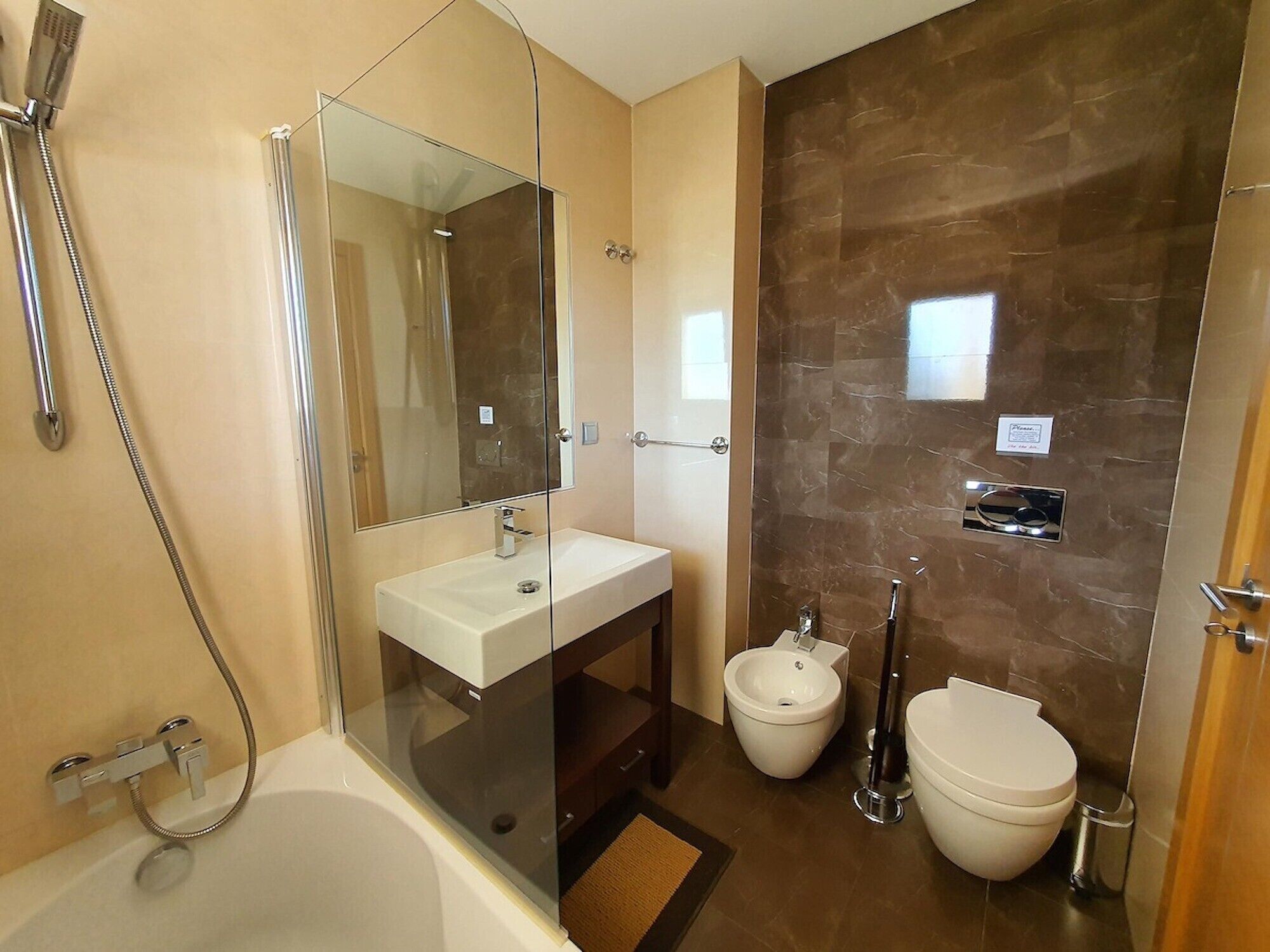 Une salle de bain moderne avec une douche à parois de verre, un lavabo blanc, un bidet et des toilettes.