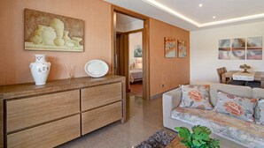 A living room with a sofa, a wooden cabinet, and a painting on the wall. - Apartment "Varandas do Sol" with Pool, Terrace & Wi-Fi (Albufeira)