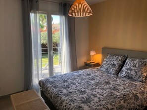 Quarto com uma cama, mesa de cabeceira, abajur e vista para uma varanda.
