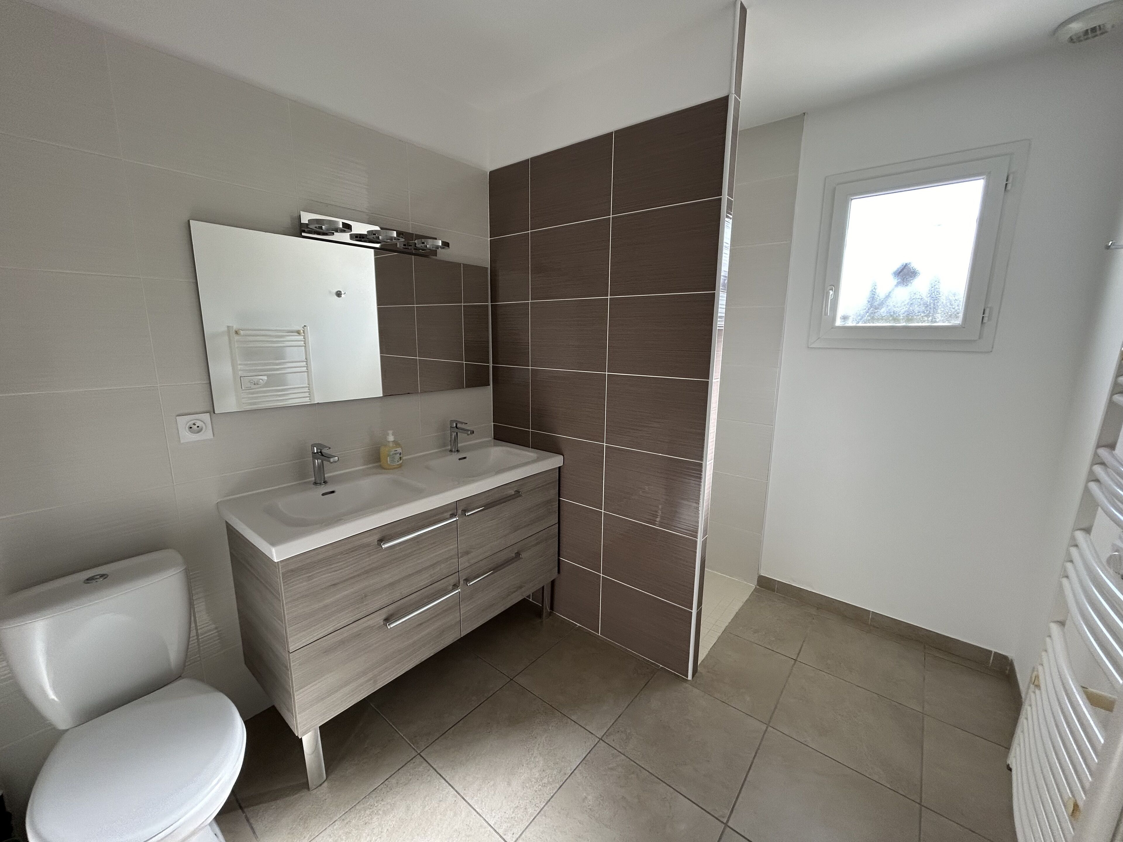 Une salle de bain moderne comprenant des toilettes, un lavabo avec un miroir et un espace douche.