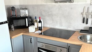 Een moderne keuken met grijze kastjes, een houten aanrecht, een ingebouwde oven, een magnetron en een koffieapparaat.