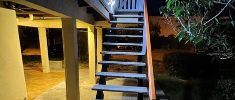A wooden staircase leading to a building entrance at night.
