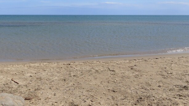 Een strand met heldere lucht en rustig water.