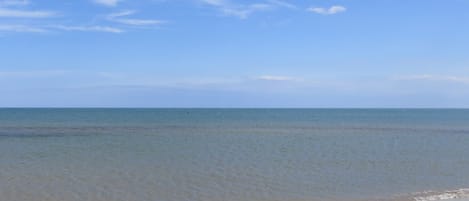 Une plage avec un ciel dégagé et une eau calme.