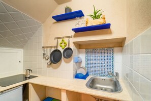 A kitchen with white tiles, a sink, a countertop, and blue shelves.