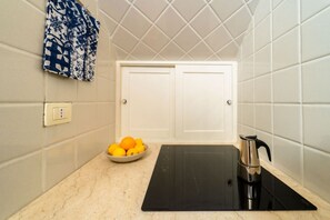 A kitchen with a black induction cooktop, a bowl of lemons, and a kettle on the counter.