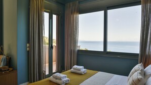 Una habitación de hotel con cama, ventana con vistas al mar y puerta que da a un espacio al aire libre.