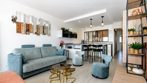 A modern living room with a grey sofa, a round coffee table, and a kitchen area with a bar. - Super apartment with sea view (Quiberon)