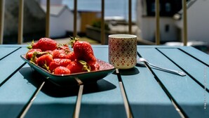 A table with a bowl of strawberries and a mug on a balcony overlooking a coastal view. - Super apartment with sea view (Quiberon)