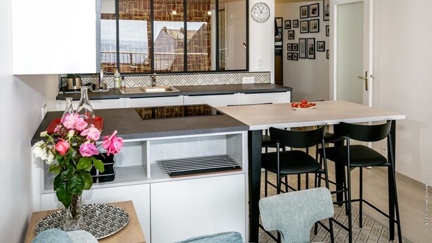 A modern kitchen with a large window, a sink, and a dining area with chairs. - Super apartment with sea view (Quiberon)