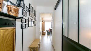 A narrow hallway with a bench, wicker baskets, framed pictures, and a large window. - Super apartment with sea view (Quiberon)