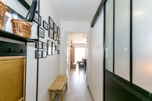 A narrow hallway with a bench, wicker baskets, framed pictures, and a large window. - Super apartment with sea view (Quiberon)