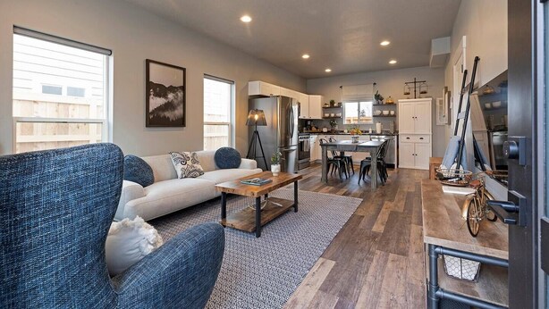 A modern living room with a sofa, coffee table, and a dining area with chairs and a table.