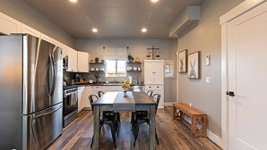 A modern kitchen with stainless steel appliances, a central island, and a dining area with a bench.