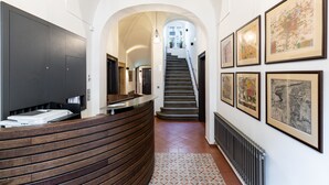 Un área de recepción con un mostrador de madera curvada, una escalera y obras de arte enmarcadas en las paredes.