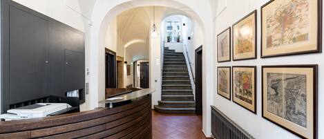 A reception area with a curved wooden desk, a staircase, and framed artwork on the walls.