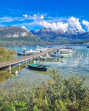 Una marina con barcos amarrados a lo largo de un muelle de madera, rodeada de montañas y agua cristalina.