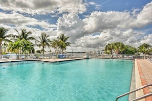 A clear blue pool with lounge chairs and palm trees, surrounded by a white fence. - Oasis House at The Nettles Island Resort! (Jensen Beach)