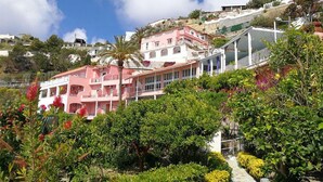 A hillside residential area with colorful buildings, a pathway, and lush greenery.