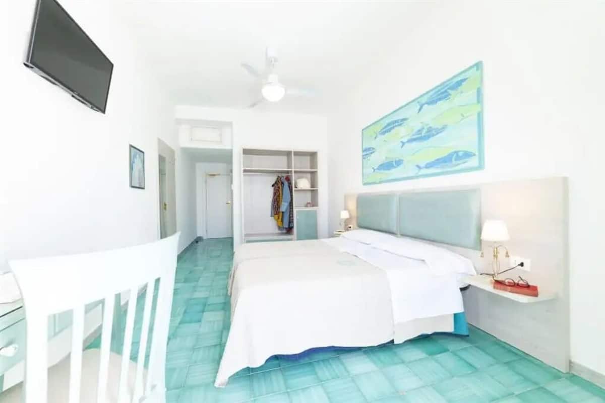 Ein Schlafzimmer mit Bett, Schreibtisch, Stuhl, Kleiderschrank und Fernseher.