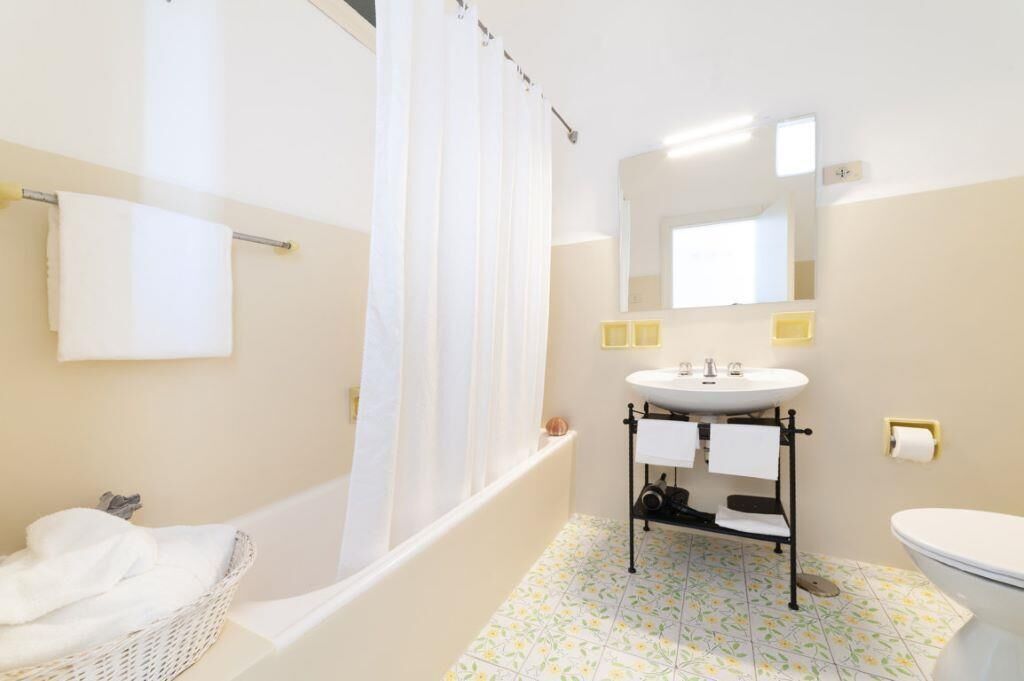 Un bagno con vasca, lavandino, water e tenda da doccia.