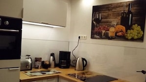A modern kitchen with a built-in oven, a coffee maker, a kettle, and a tablet on the countertop. - Modern vacation apartment in a quiet location (Meißner)
