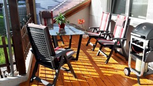 An outdoor patio with a table, chairs, a grill, and a potted plant. - Modern vacation apartment in a quiet location (Meißner)