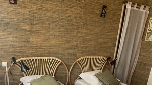 A room with two single beds, a wooden wall, a patterned floor, and a curtain. - Country house ! 5 minutes from the village center. (Caromb)